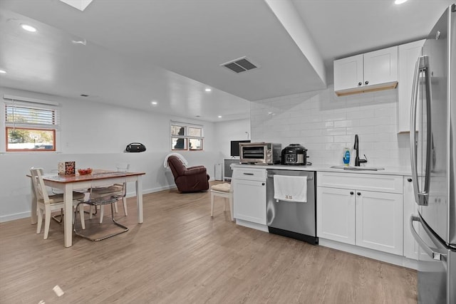 kitchen featuring light wood-type flooring, stainless steel appliances, a healthy amount of sunlight, and light countertops