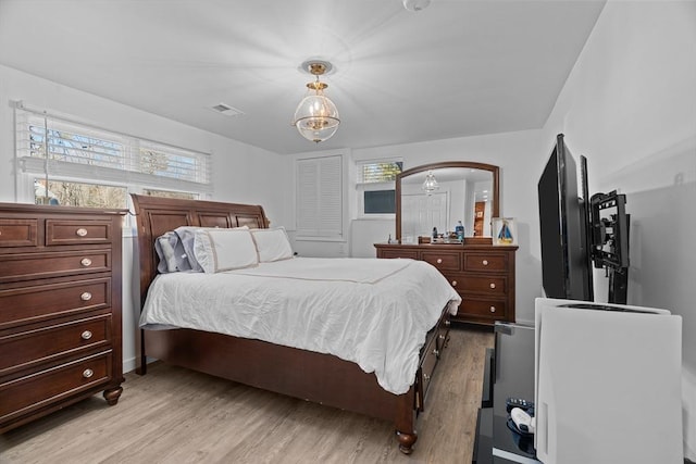 bedroom featuring light wood finished floors, visible vents, and arched walkways