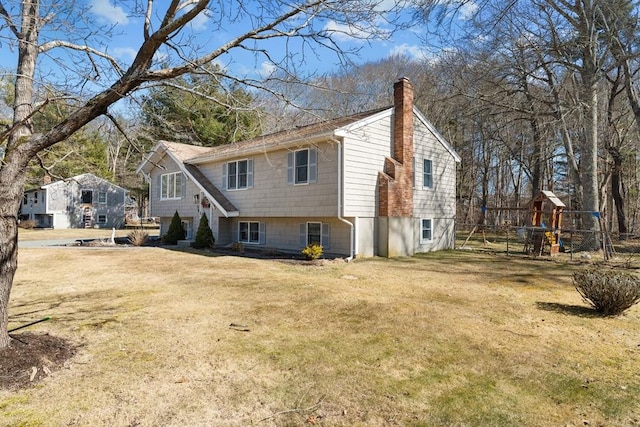 exterior space with a playground, a yard, driveway, and a chimney