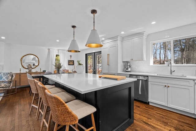 kitchen featuring a sink, dark wood finished floors, light countertops, decorative backsplash, and dishwasher