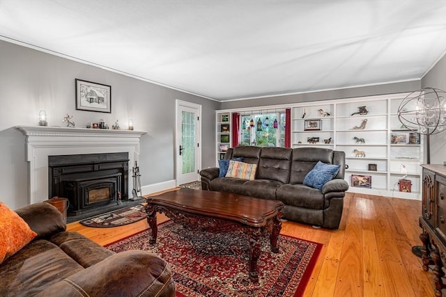 living area with baseboards, a fireplace, ornamental molding, and wood finished floors