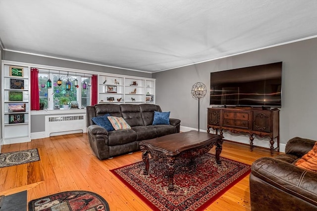 living room featuring radiator, crown molding, baseboards, and hardwood / wood-style flooring