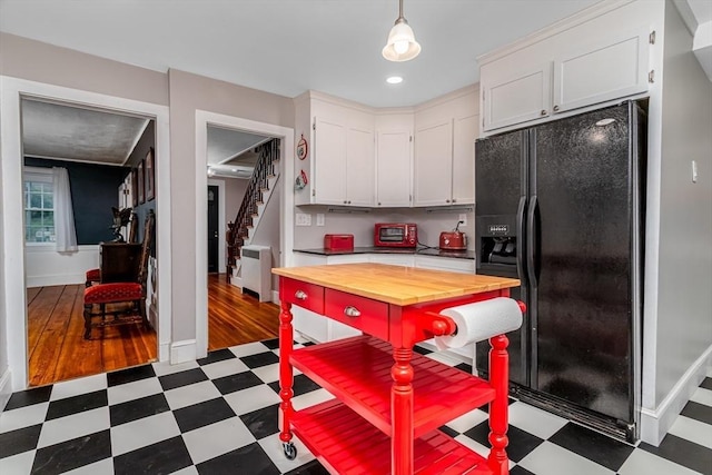 kitchen featuring baseboards, black fridge with ice dispenser, dark floors, white cabinetry, and wooden counters