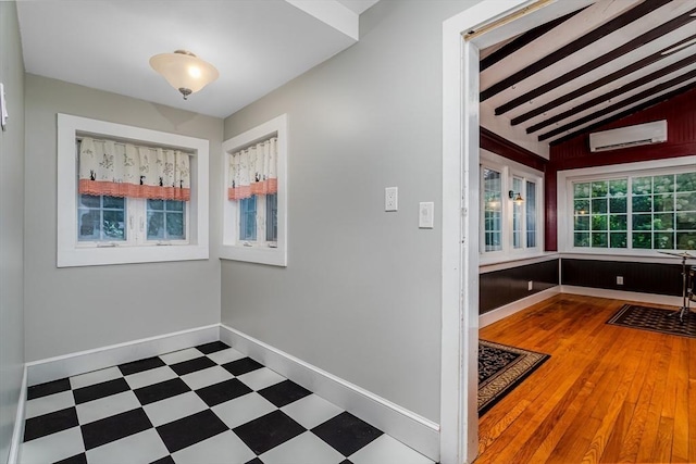 interior space with vaulted ceiling, a wall mounted air conditioner, baseboards, and tile patterned floors