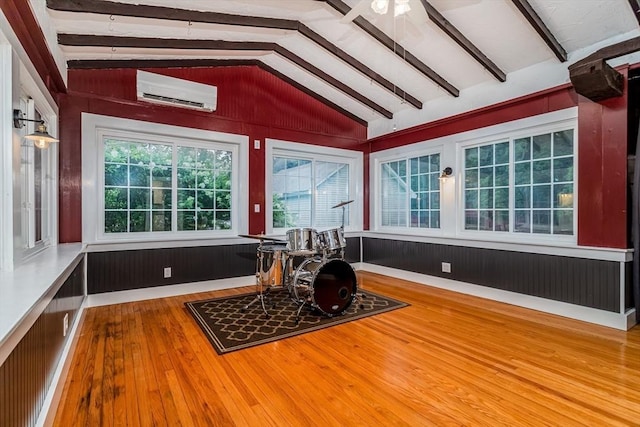 sunroom with a ceiling fan, an AC wall unit, and lofted ceiling with beams