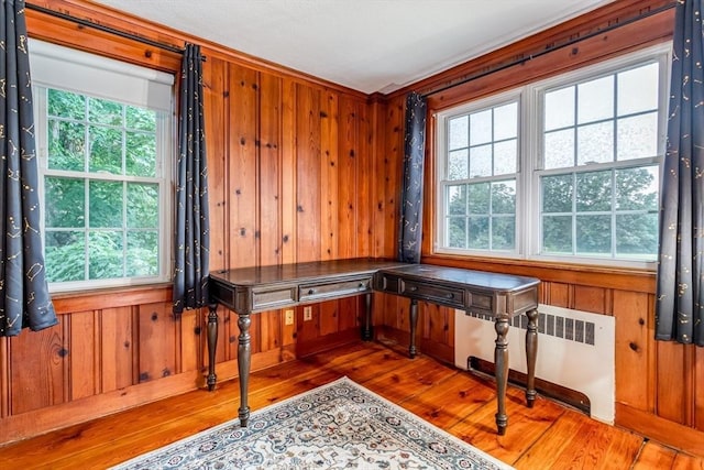 office with hardwood / wood-style floors, wooden walls, and radiator heating unit