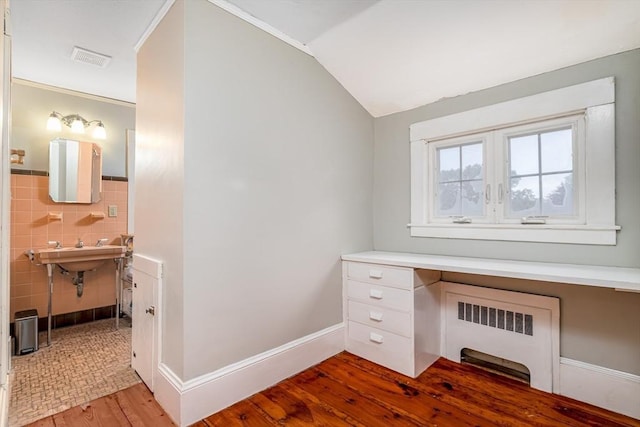 home office with tile walls, radiator, visible vents, vaulted ceiling, and wood finished floors