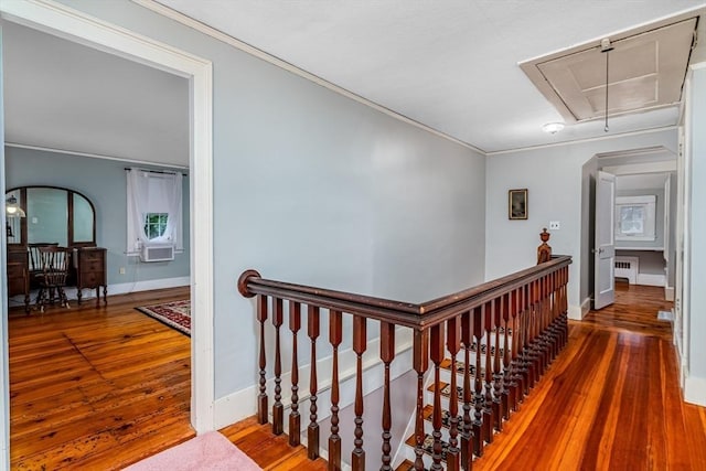 corridor with baseboards, wood finished floors, an upstairs landing, and attic access