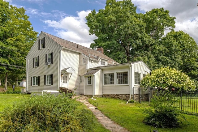 rear view of house with a yard, a chimney, and fence