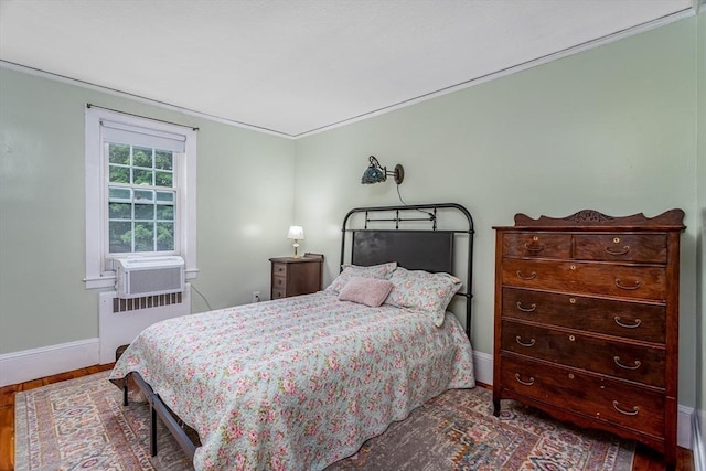 bedroom featuring radiator heating unit, wood finished floors, and baseboards