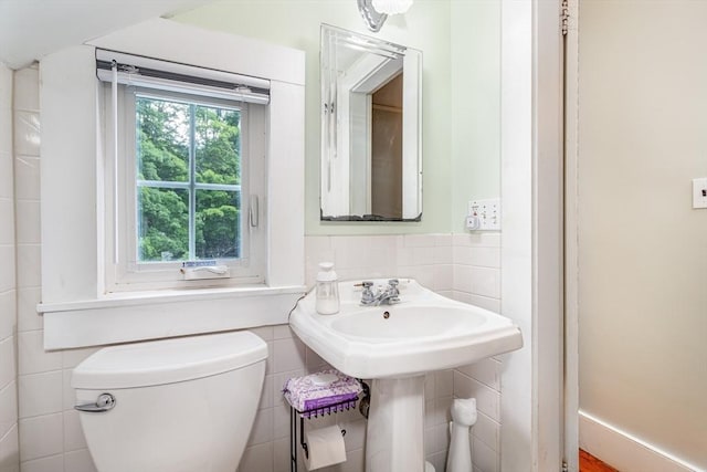 bathroom with toilet and tile walls