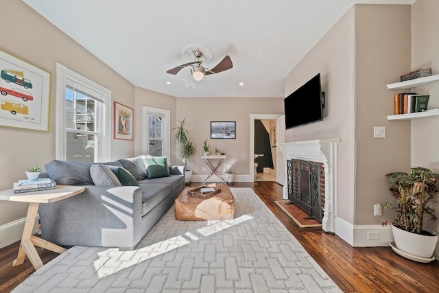 living area featuring recessed lighting, a fireplace, a ceiling fan, baseboards, and dark wood-style floors