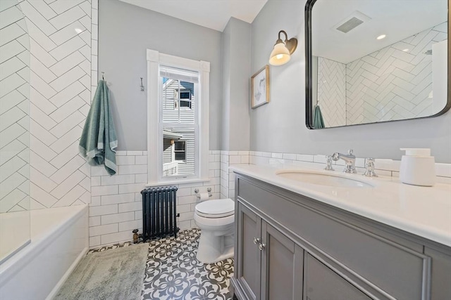 full bathroom featuring toilet, visible vents, vanity, tile walls, and radiator heating unit