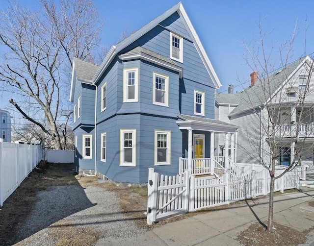 view of front of home with a fenced front yard, driveway, and a porch