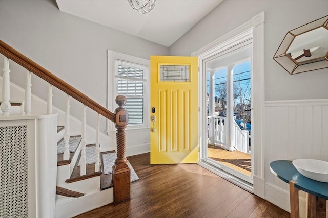 foyer entrance with lofted ceiling, wainscoting, wood finished floors, ornate columns, and stairs