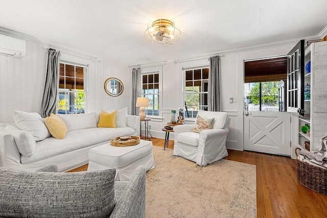 living area with wood finished floors, ornamental molding, and a wall mounted AC