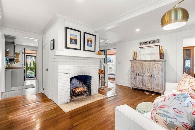 living room with crown molding, a brick fireplace, wood finished floors, and a healthy amount of sunlight