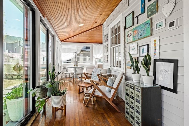sunroom / solarium with wooden walls, wooden ceiling, hardwood / wood-style flooring, and lofted ceiling