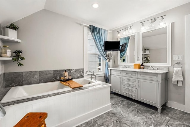 full bathroom featuring double vanity, a sink, a bath, and vaulted ceiling
