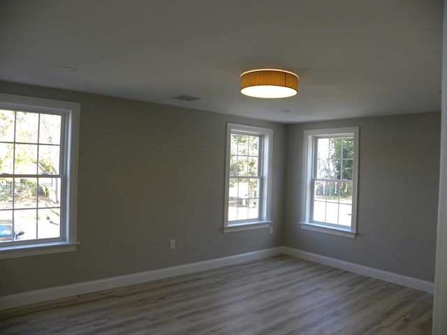 unfurnished room with visible vents, baseboards, and wood finished floors