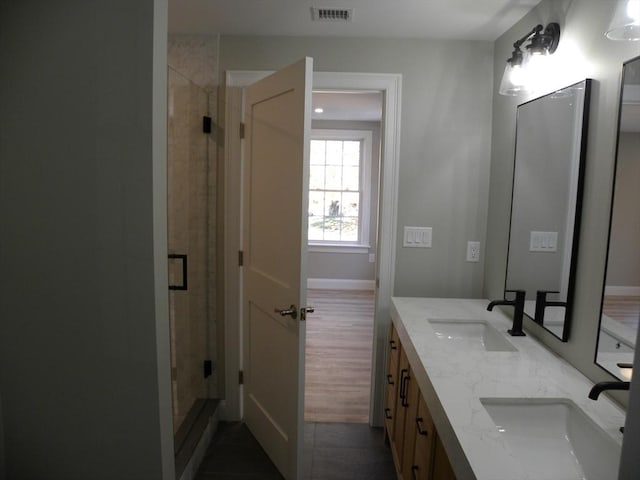 full bathroom featuring a sink, visible vents, double vanity, and a shower stall