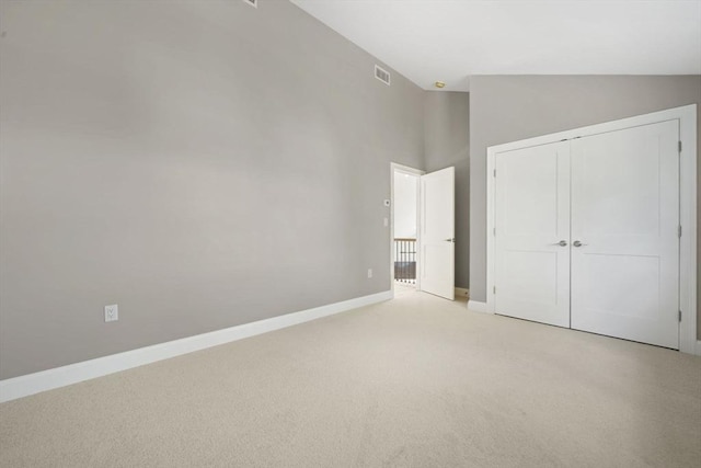 unfurnished bedroom featuring visible vents, baseboards, high vaulted ceiling, a closet, and light carpet