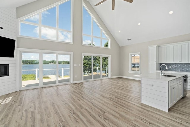 interior space featuring a sink, open floor plan, light wood-style floors, tasteful backsplash, and a large fireplace