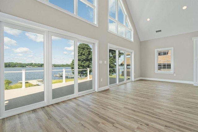 unfurnished sunroom featuring visible vents, a water view, and lofted ceiling