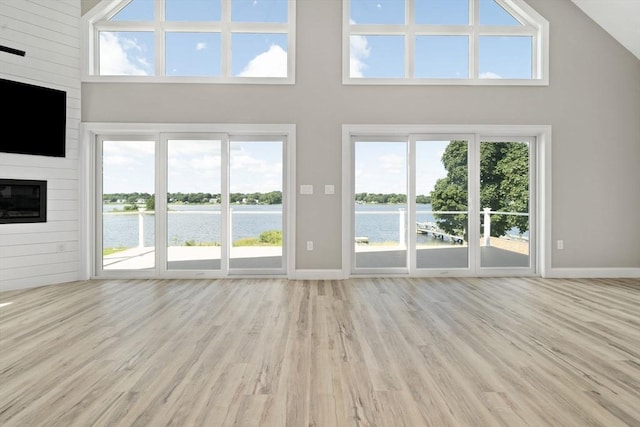 unfurnished living room with a wealth of natural light, a water view, and wood finished floors