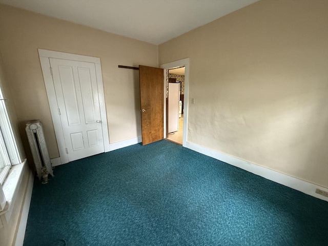 unfurnished bedroom featuring radiator heating unit, carpet flooring, and baseboards