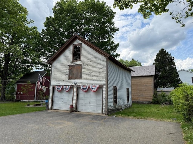 view of property exterior with asphalt driveway and a lawn