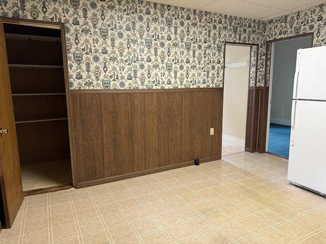 unfurnished room with wainscoting, wallpapered walls, and wooden walls