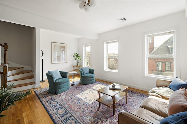 living area featuring visible vents, stairway, baseboards, and light wood-type flooring