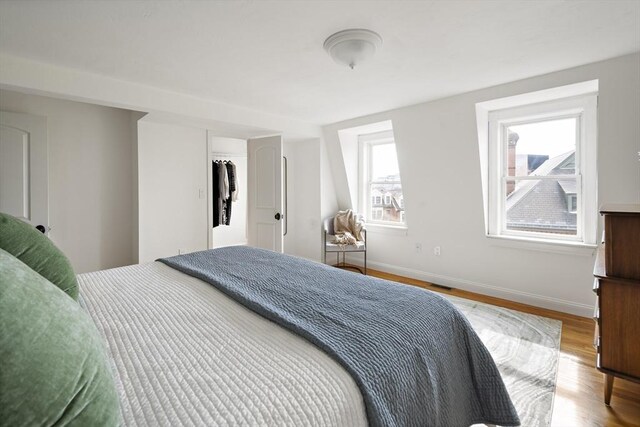 bedroom with visible vents, wood finished floors, and baseboards