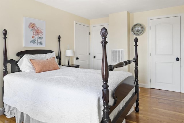 bedroom featuring visible vents, baseboards, and wood finished floors