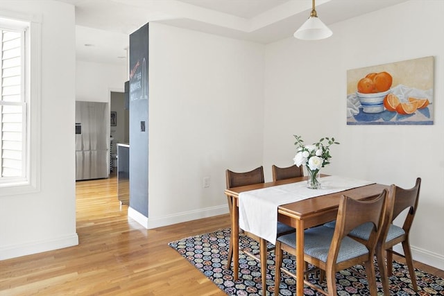 dining space featuring light wood-type flooring and baseboards