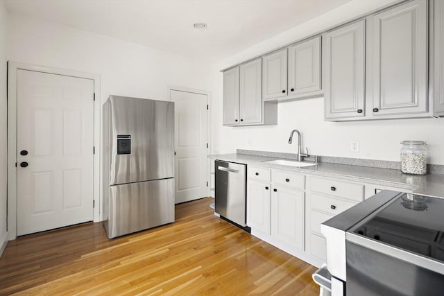 kitchen featuring a sink, light wood-style floors, appliances with stainless steel finishes, and light countertops