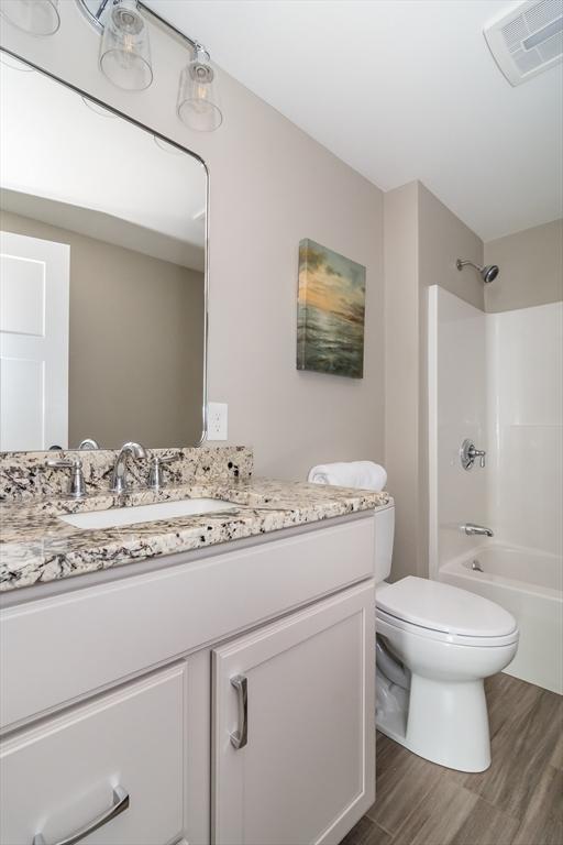 32 Charles St, Natick, MA 01760 - bathroom featuring wood finished floors, vanity, toilet, and shower / bathtub combination