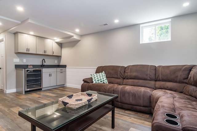 32 Charles St, Natick, MA 01760 - living room featuring beverage cooler, light wood-style flooring, bar with sink, wainscoting, and recessed lighting
