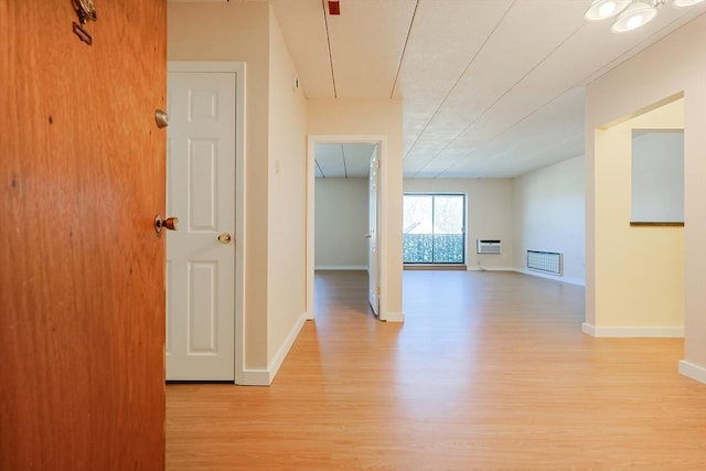 hallway with a wall unit AC and light wood-type flooring