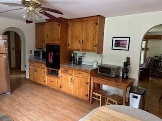 kitchen with light hardwood / wood-style floors, oven, and ceiling fan