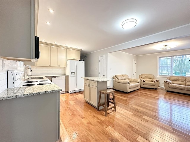 kitchen with a center island, light stone counters, backsplash, white appliances, and a breakfast bar