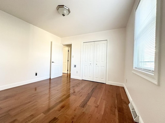 unfurnished bedroom with dark hardwood / wood-style floors and a closet