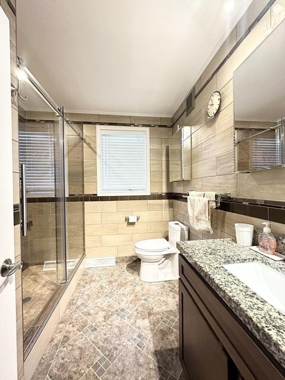 bathroom with vanity, toilet, tile walls, and walk in shower