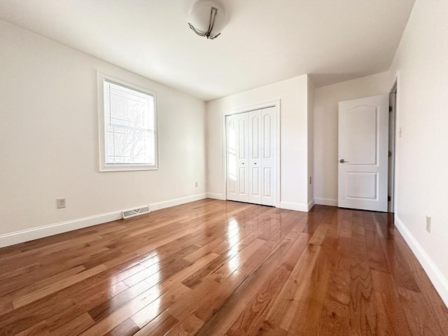 unfurnished bedroom featuring wood-type flooring and a closet