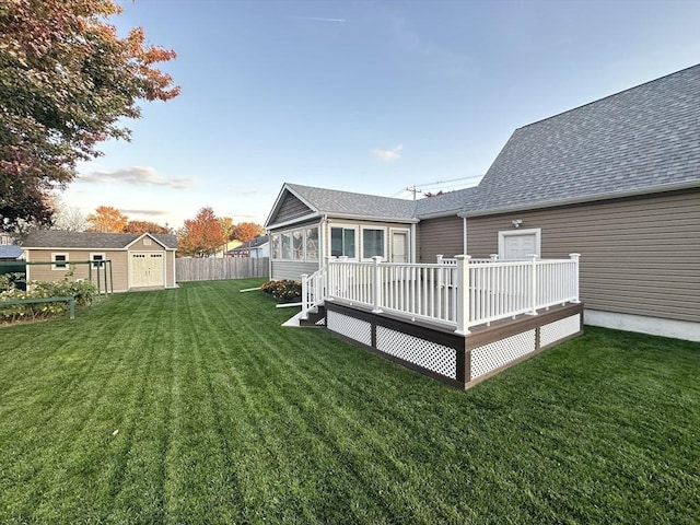 rear view of house featuring a lawn, a wooden deck, and a storage unit