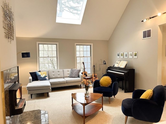 living area featuring light carpet, a skylight, visible vents, and high vaulted ceiling