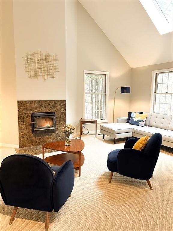 living room featuring a high end fireplace, carpet flooring, and high vaulted ceiling