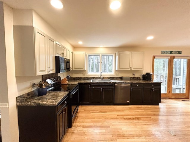 kitchen with a healthy amount of sunlight, black appliances, light wood-style floors, white cabinetry, and a sink