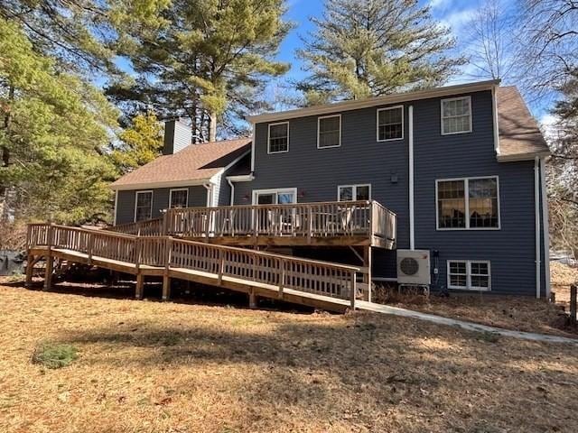 rear view of house with a deck, ac unit, and a chimney